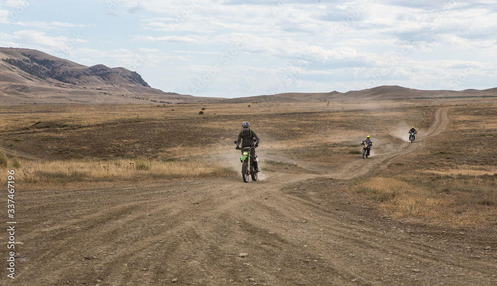 Cross-country motorcyclists ride on dirt road
