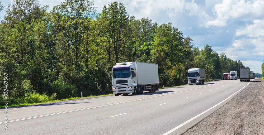 Trucks deliver cargo in opposite directions on a suburban highway Trucks deliver cargo in opposite directions on a suburban highway