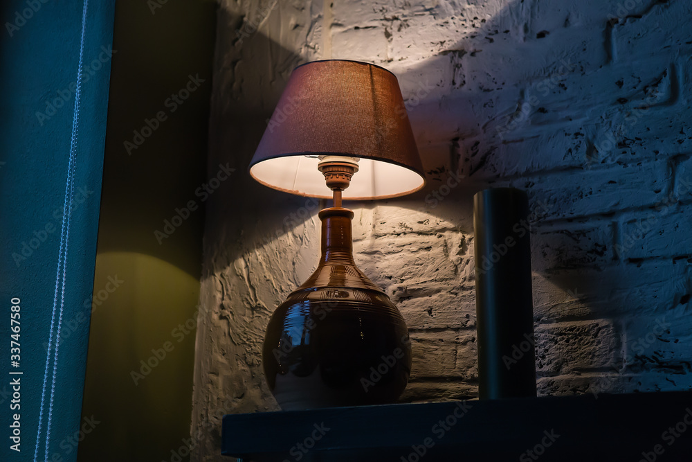 Stylish table lamp illuminating a brick wall