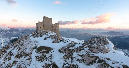 Aerial, drone shot towards the Rocca Calascio castle ruins on snowy Gran Sasso mountains, during sunset, in Abruzzo, Italy photo