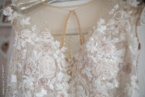 White wedding dress with lace hanging on a hanger.