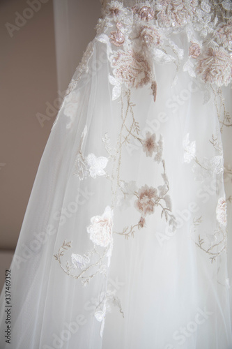 White wedding dress with lace hanging on a hanger.