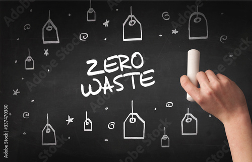 Hand drawing ZERO WASTE inscription with white chalk on blackboard, online shopping concept