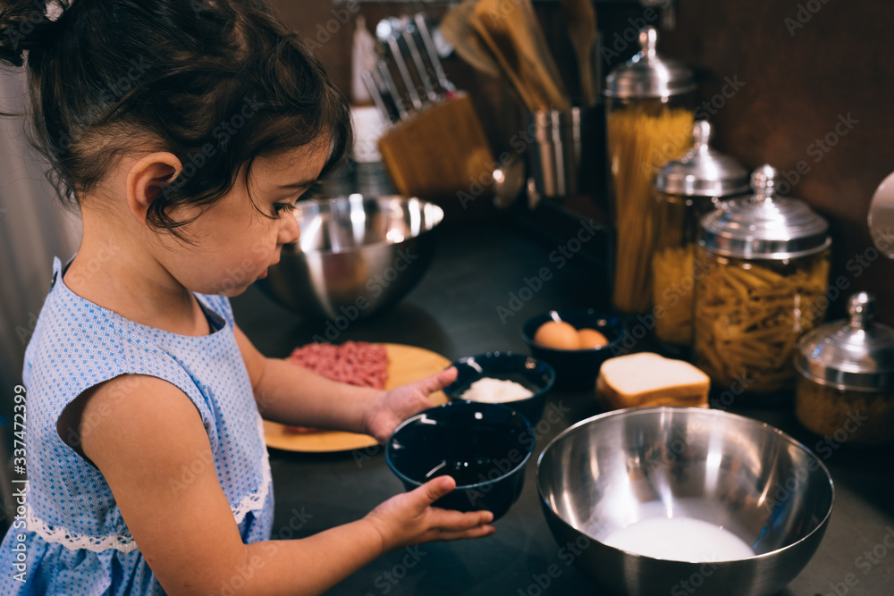 little girl while preparing meatballs in the kitchen during the quarantine little girl while preparing meatballs in the kitchen during the quarantine