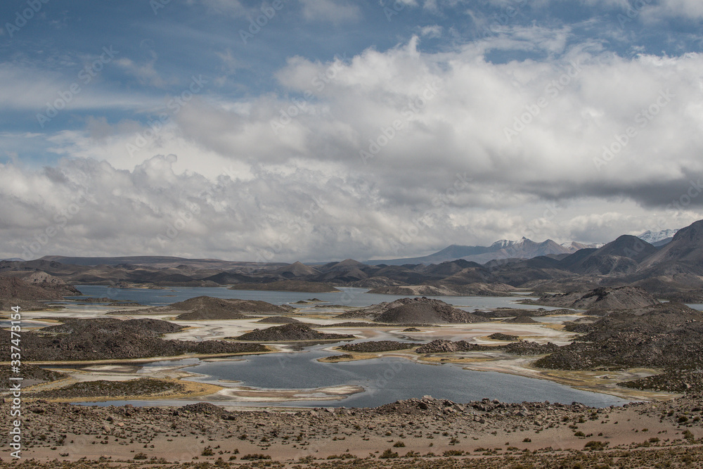 Rugged desert lake under the high Andes mountains surrounded by clouds