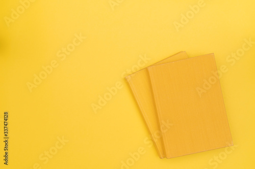 Two yellow books with blank cover on a yellow background. Hard cover. Top view. Copy space