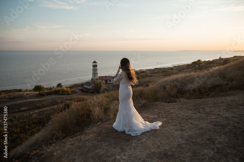 bride looks at the sea and the lighthouse