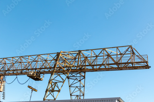 Vintage working gantry crane rusty yellow, bottom view, close-up against a blue spring sky