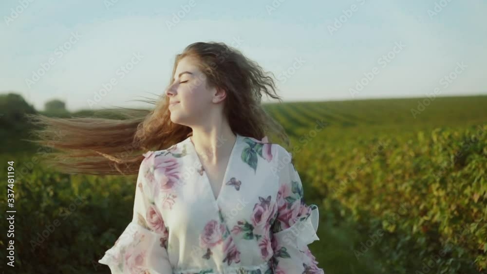 Happy young lady with long hair, wore in dress spinning among spacious field Happy young lady with long hair, wore in dress spinning among spacious field
