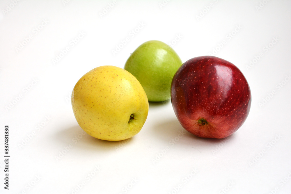 Три разноцветных яблока красное зеленое желтое на белом фоне
