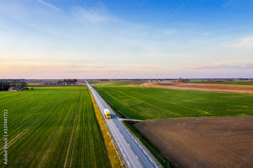 Aerial view of a highway passing through spring agricultural fields at sunset