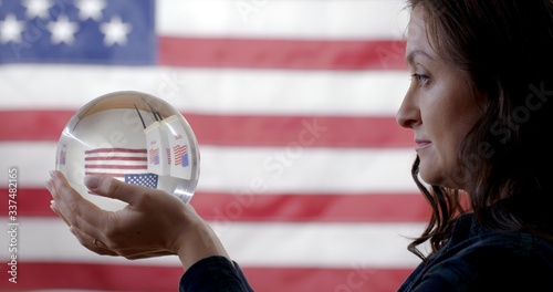 Photography CU profile young Caucasian woman holding up crystal ball showing voting booths i