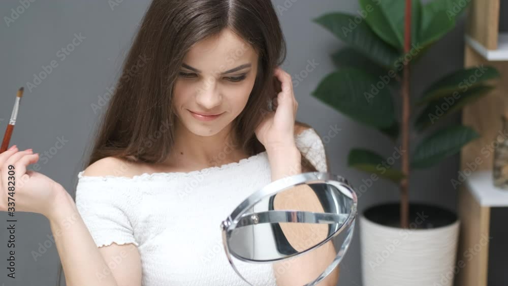Girl draws eyelashes while looking in the mirror Girl draws eyelashes while looking in the mirror