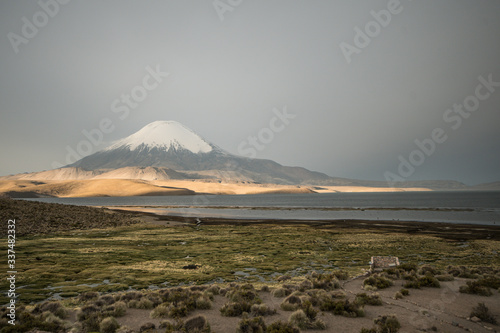 Andean laguna under the volcano with glacier on top at sunset