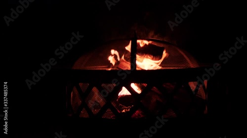 Burning wooden logs in an outdoor fireplace on a dark night.