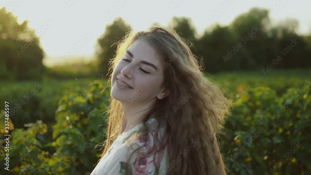 Lady with long hair, wore in dress spinning and posing at camera in field Lady with long hair, wore in dress spinning and posing at camera in field