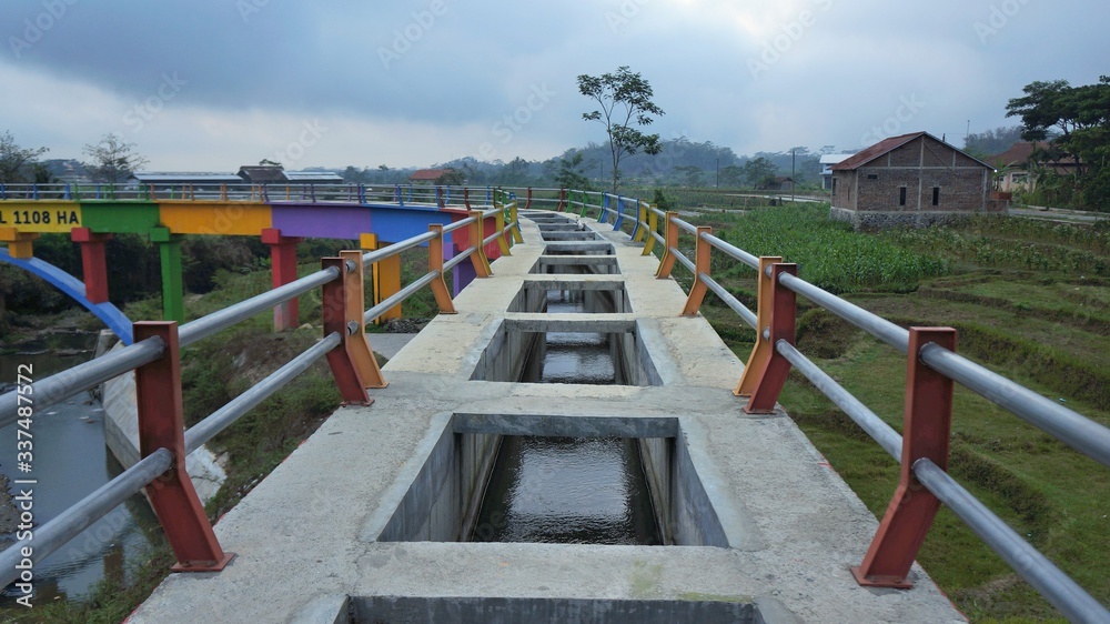 red and white color agricultural irrigation river bridge in central java in the morning red and white color agricultural irrigation river bridge in central java in the morning