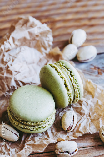 Deux macarons à la pistache et pistaches dans leur coque sur un fond bois naturel