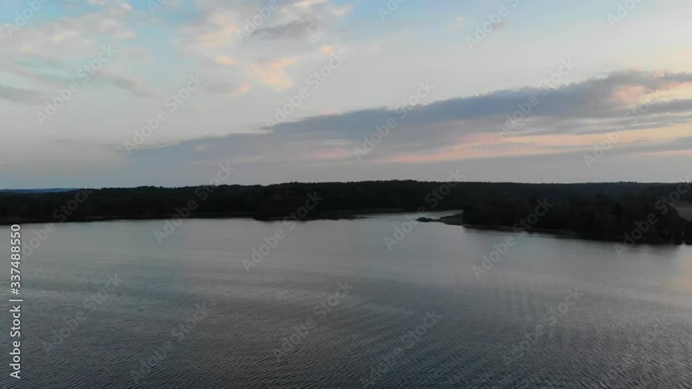 Aerial shot camera crane down on archipelago water with a colorful sunset in background Aerial shot camera crane down on archipelago water with a colorful sunset in background
