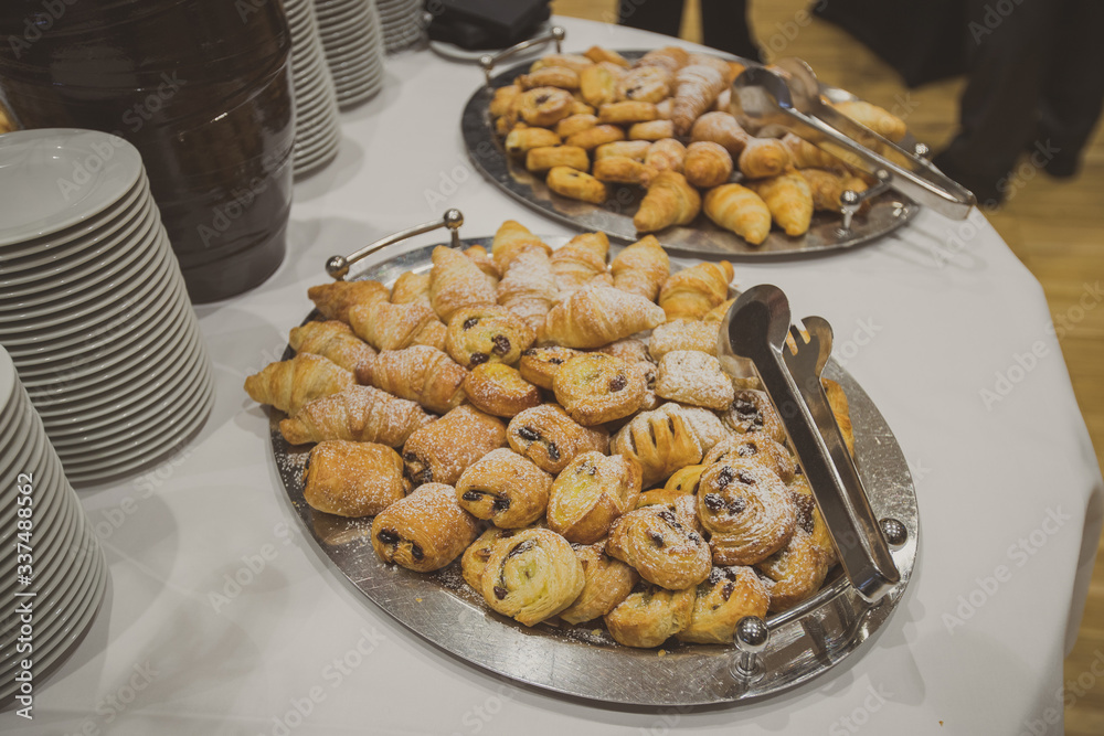Croissants and other pastry products on a display at a conference or a banquet as a part of a breakfast meal. Croissants on a white table
