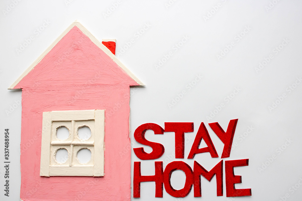 A small pink house next to the words, a call to stay at home. Warning against the covid-19 coronavirus or epidemic A small pink house next to the words, a call to stay at home. Warning against the covid-19 coronavirus or epidemic