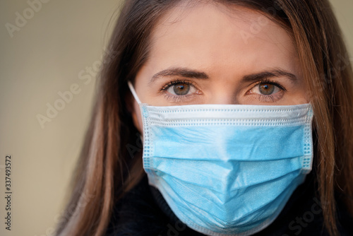 Young woman wearing disposable blue virus face mouth nose mask  closeup portrait. Coronavirus covid-19 outbreak prevention concept