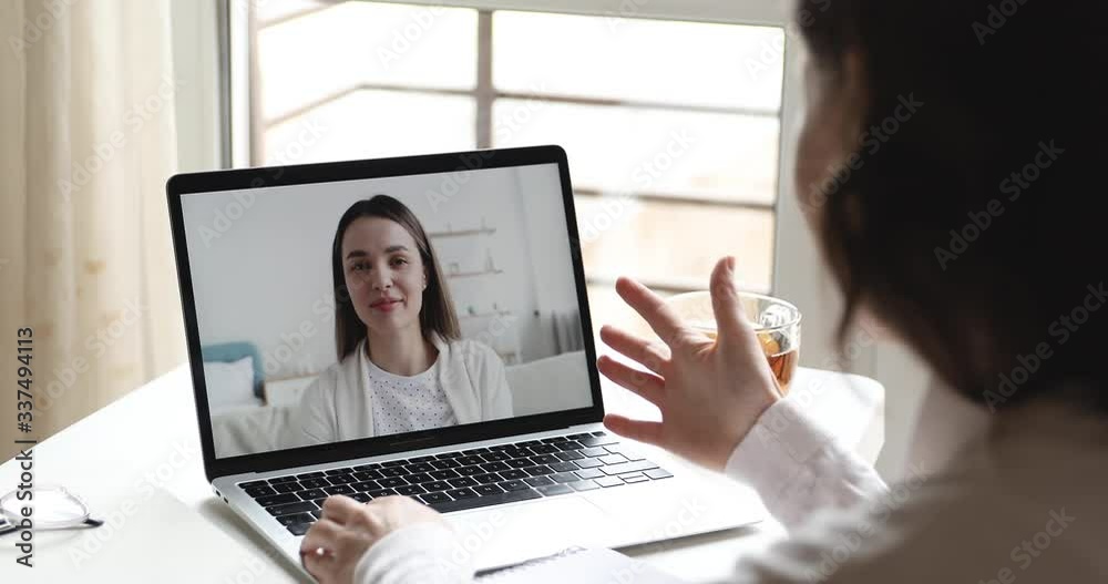 Friends on video chat concept. Over shoulder close up view of young user video calling talking with woman online on computer laptop screen on table. Webcam virtual conference lifestyle communication Friends on video chat concept. Over shoulder close up view of young user video calling talking with woman online on computer laptop screen on table. Webcam virtual conference lifestyle communication