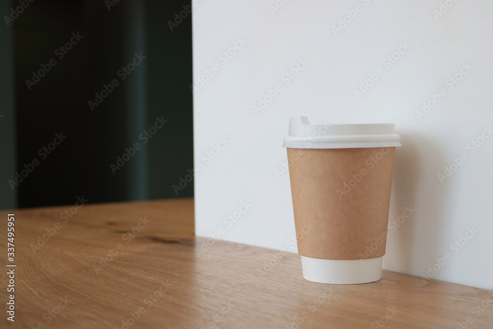 Mock up with a cup of coffee. A glass is on the table in a cafe, selling coffee in the background. Coffee to go. Light walls. Wooden table. Cafe. Disposable cup Mock up with a cup of coffee. A glass is on the table in a cafe, selling coffee in the background. Coffee to go. Light walls. Wooden table. Cafe. Disposable cup