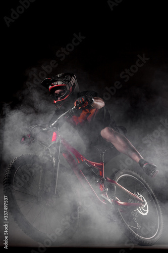 Male bicyclist riding dirty downhill mountain bike and falling. Studio shot with smoke in the air