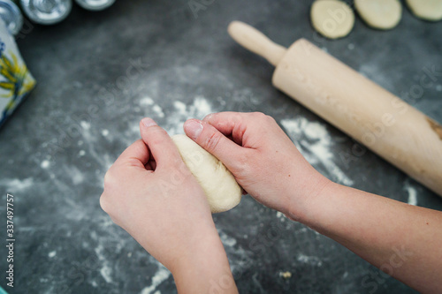 Close up on hand of unknown caucasian woman female girl making bread knead the dough pastry kneading on the kitchen table at home top view © Miljan Živković