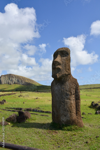 singular Ancient maoi statue in landscape with mountain and feilds