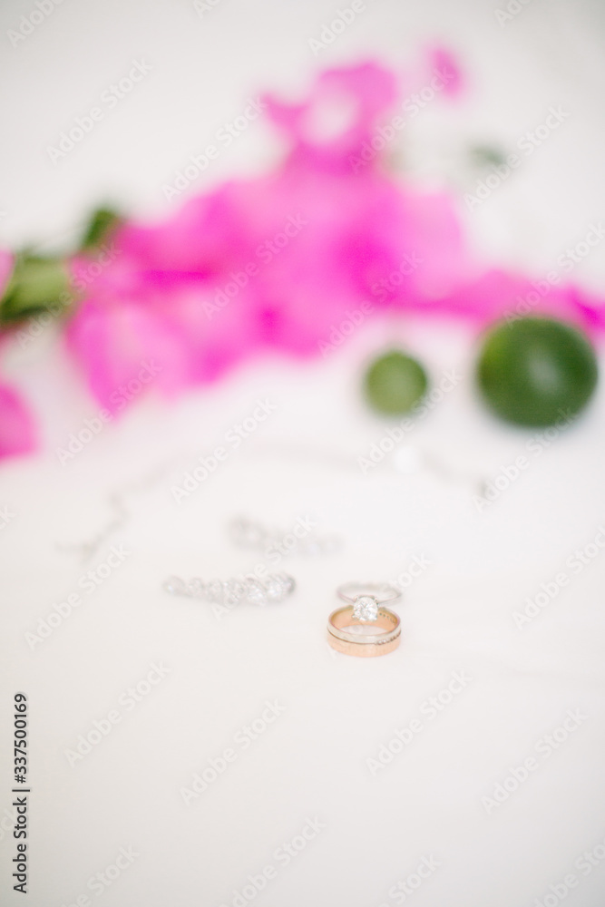 Wedding rings and jewelry. On a white background and pink bougainvillea leaves and lime. Wedding rings and jewelry. On a white background and pink bougainvillea leaves and lime.