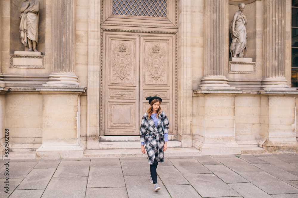 A girl in a beautiful coat stands near the Louvre. A girl in a beautiful coat stands near the Louvre.