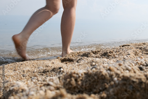 Girl walks along the sandy beach. Close up of woman's legs in motion © alex_shi