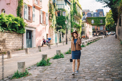 A beautiful young woman in a brown jacket walks in the early morning on the famous Montmartre hill in Paris