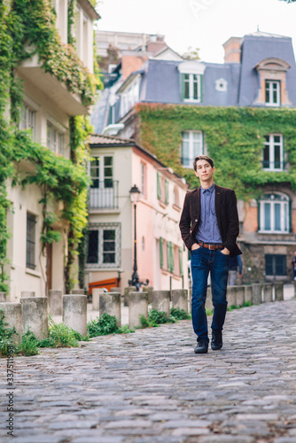 a man in a jacket and jeans walks in Montmartre, Paris