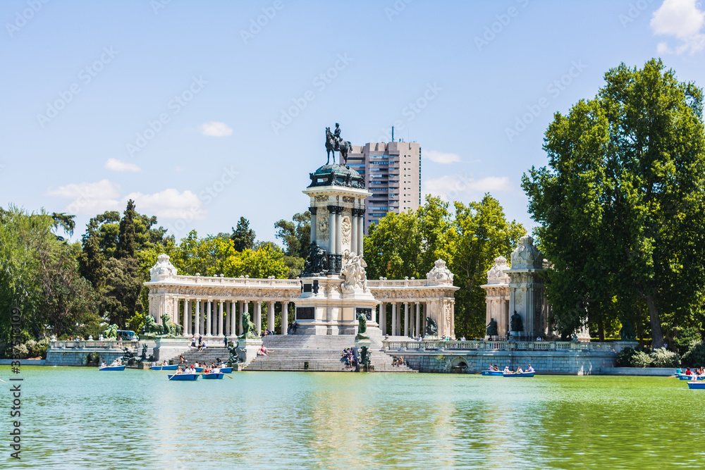 The Monument to Alfonso XII, tourists boating in a lake people enjoy summer evening in Buen Retiro Park
