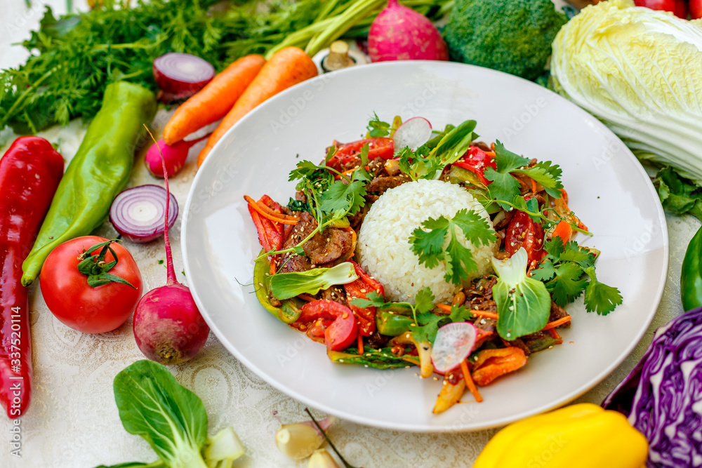 Thai meat with vegetables on a decorated table in a white plate Thai meat with vegetables on a decorated table in a white plate