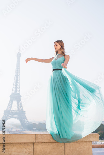 Beautiful girl in an azure evening dress in Paris with the Eiffel tower in the background. © Aleksei Zakharov