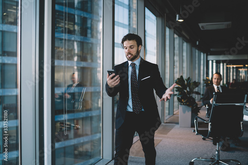 Furious male entrepreneur in suit disappointed with bad nes and mails using mobile phone for sending message,expressive caucasian businessman screaming on smartphone having problem with using device © BullRun
