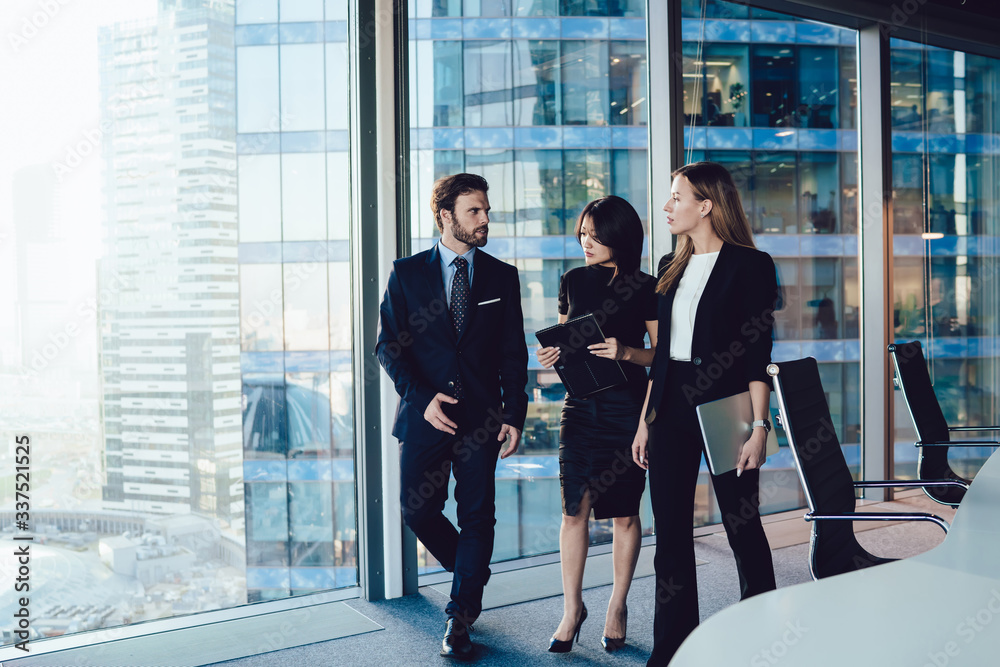 Confident male and female colleagues in formal elegant outfit walking in office having serious conversation about job, professional male manager explaining information to 30s women employees Confident male and female colleagues in formal elegant outfit walking in office having serious conversation about job, professional male manager explaining information to 30s women employees