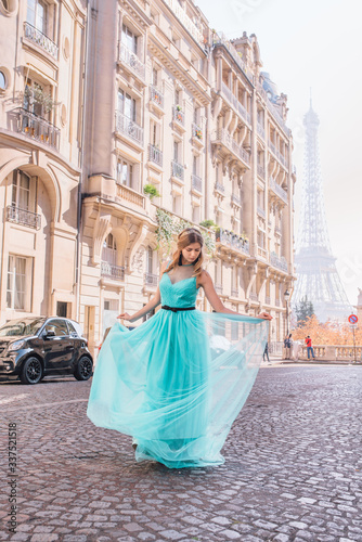 Beautiful young girl in a dress on the street with a view of the Eiffel tower