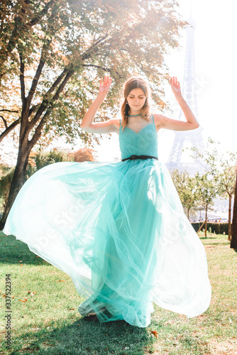 Beautiful girl in an azure evening dress in Paris with the Eiffel tower in the background.