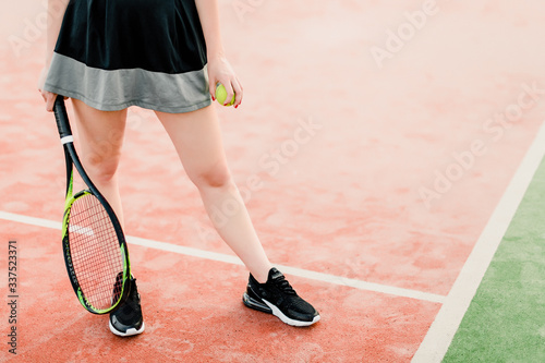 female legs and tennis racket with ball on the court