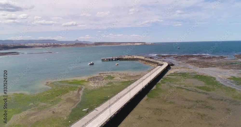Drone view of bridge, harbor, sea, beach and ships in Patagonia, Argentina. Wide shot in high altitude and crane shot moving vertically down,. Seagulls appear flying close to camera. Drone view of bridge, harbor, sea, beach and ships in Patagonia, Argentina. Wide shot in high altitude and crane shot moving vertically down,. Seagulls appear flying close to camera.