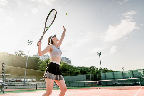 teenage tennis player tossing ball up before hitting it with racket © Anastasia