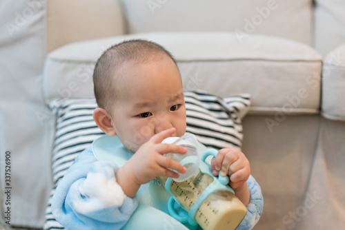 Baby in pajamas eating milk in the room