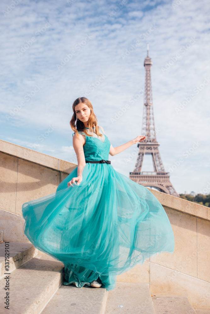Fototapeta premium a girl in Paris in a green dress against the backdrop of the Eiffel tower elegant on the Trocadero square in summer a luxurious beautiful figure