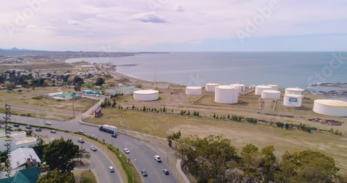 Drone shot of houses, highway with traffic, houses, sea, harbors and oiltanks in Comodoro Rivadavia in Patagonia, Argentina. Panoramic wide shot panning to the right revealing each area. photo