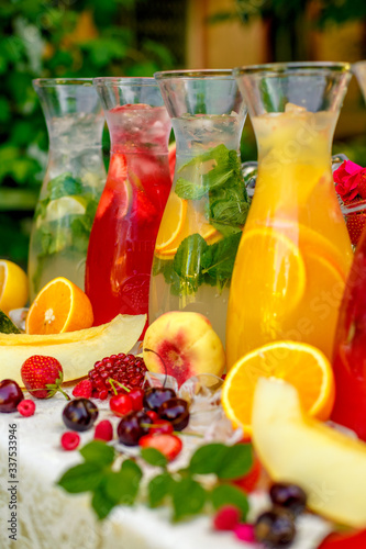 fresh lemonade collection (watermelon, orange, lemon, strawberry and berry) in the street, on a wooden table with fruit